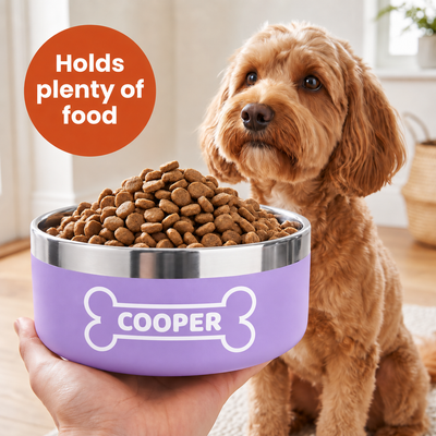 Hand holding a lilac Personalised Nameplate Dog Bowl heaped with kibble, the name COOPER printed inside a bone outline, cockapoo sitting alongside