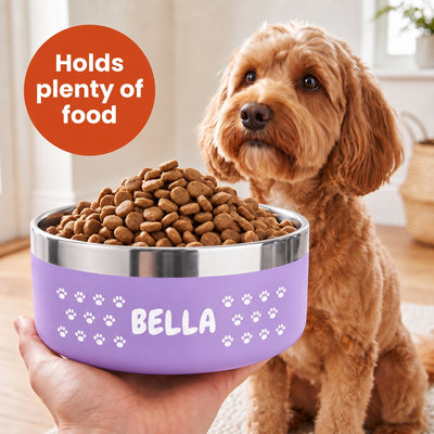 Hand holding a lilac Personalised Pattern Dog Bowl heaped with kibble, the name BELLA set into a band of white paw prints, cockapoo alongside